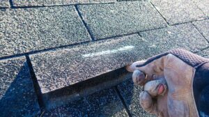 Homeowner reviews a roofing contract beside storm-damaged shingles and a camera with repair photos.
